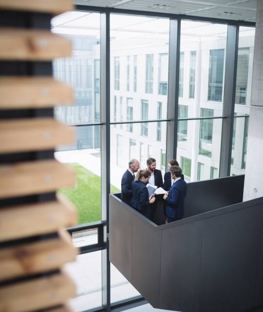 Group of businesspeople having a discussion near staircase in office